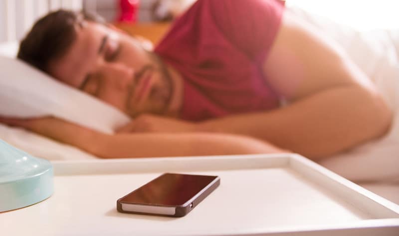 Person sleeping with cell phone next to them